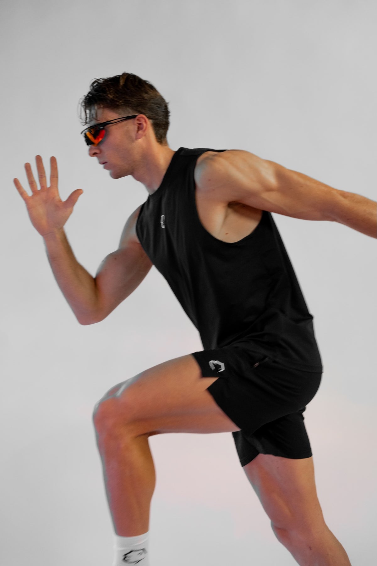 Modello in corsa di profilo con pantaloncini sportivi neri